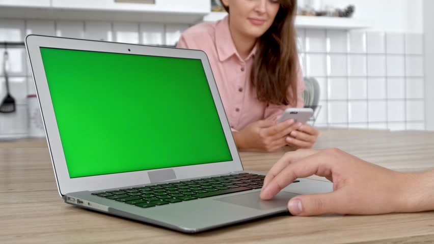 Couple In Kitchen Using Laptop to Research Home Improvement Ideas. Screen image can easily be replaced using the included clipping path.