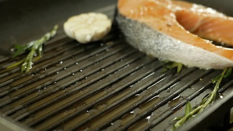 Fresh salmon steaks being placed on a hot grille to cook, close-up
