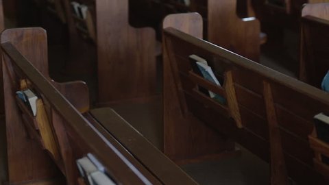 A Mennonite woman sits in an empty church pew and flips through a hymnal.