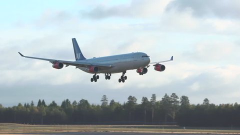 oslo airport norway - ca october 2018: huge airplane airbus a340 arrival landing back lit panning right side view scandinavian airlines