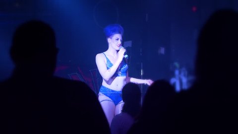 Female stand-up comedian performing on stage in lingerie, underwear