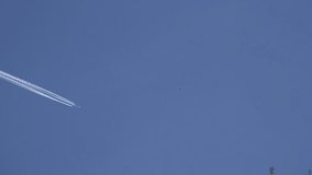 Airplane plane fly high in blue sky leaving white smoke marks. Static closeup shot. 4K UHD video clip.