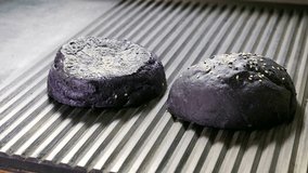 Black bread. Close-up shot of two halves of hamburger bun are being fried in a broiler pan for burger. 4K