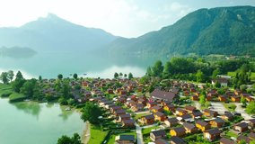 Aerial View on the mountain village and lake in morning time in summer sunny day under sun light. Beautiful mountains landscape view. Drone 4K Video.
