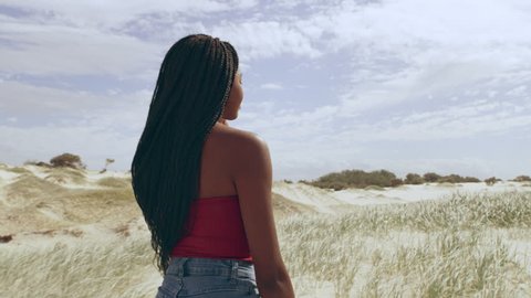 Young attractive girl walking among sand dunes smiling in Australia. Medium close on 4k RED camera.