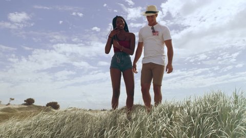 Couple standing at the edge of beach holding each other and saying goodbye, sand dunes in the background in Australia. Wine shot on 4k RED camera.