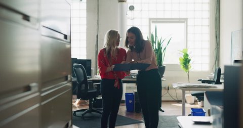 Female employee gets mad at female coworker and throws papers in office hallway during the daytime. Wide long shot on 4K RED camera on a gimbal.
