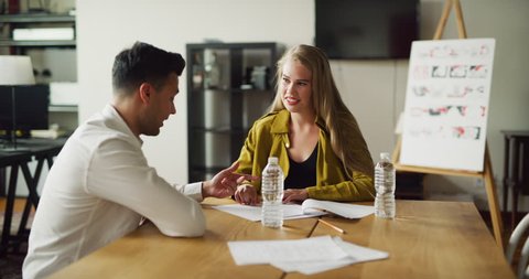 Male and female coworkers have meeting at wood desk in modern tech office during the day. Medium shot with soft lighting on 4K RED camera.