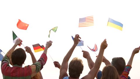 People waving different flags outdoors. Crowd of international people. Morning sky background.