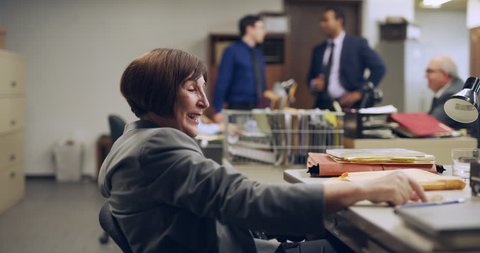 Unprofessional woman pouring an alcoholic beverage at her desk in interior lawyer office with bright interior lighting. Wide to Medium shot on 4k RED camera.