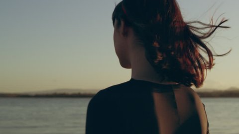 Woman walking along beach smiling as sun sets behind her in Australia.Medium close on 4k RED camera.
