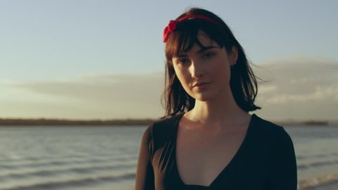 Woman model walking on a beach smiling as sunsets with lake in the background in Australia. Medium close on 4k RED camera.