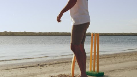 Cricket player striking ball on the beach with lake and sky in the background in Australia. Medium close on 4k RED camera.