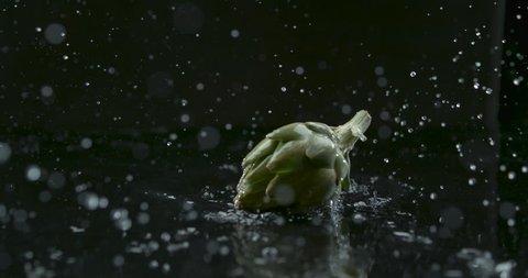 Globe artichoke beautifully drops in water and splashes over black background closeup in ultra slow motion with 4k Phantom Flex camera. Stock-video