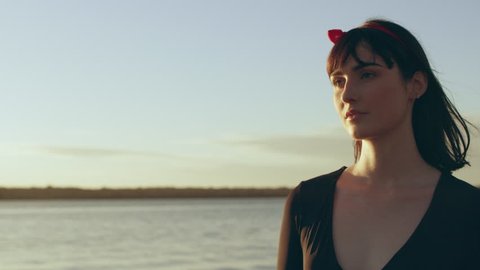 Woman model walking by on a beach at sunset with lake in the background in Australia. Medium close on 4k RED camera.