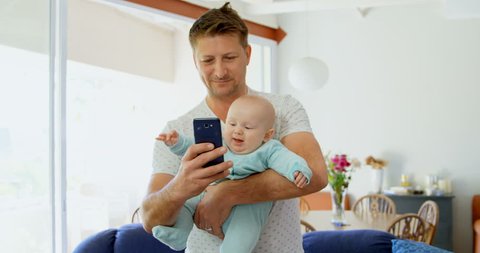 Father and baby boy using mobile phone in living room at home Social distancing and self isolation in quarantine lockdown for Coronavirus Covid19
