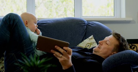 Father and baby boy using digital tablet in living room at home Social distancing and self isolation in quarantine lockdown for Coronavirus Covid19