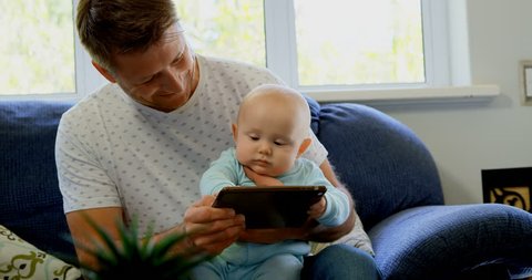 Close up of father and baby boy using digital tablet in living room at home Social distancing and self isolation in quarantine lockdown for Coronavirus Covid19