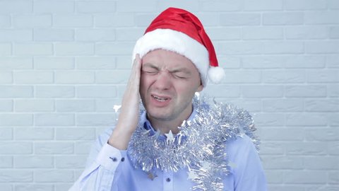 Young man with Santa Claus hat having headache