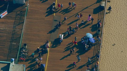 Aerial view of people walking on Santa Monica Pier shoreline on a sunny day in Los Angeles, California. Shot on 4K RED camera.