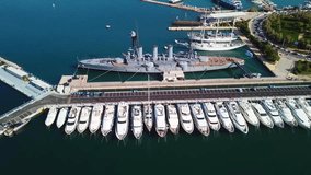 Aerial drone bird's eye view video of small port and Park of Maritime Tradition where historic Averof warship is docked, Floisvos, Faliro Marina, Attica, Greece