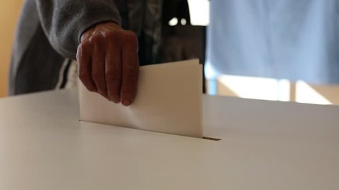 Video of a person casting a ballot at a polling station, during elections.