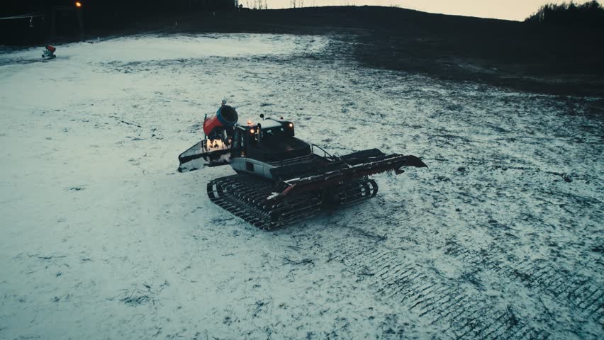 Aerial shot: Snowcat preparing a slope at skiing resort, 4k