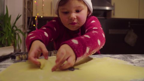 Crane shot. Little girl carves Christmas cookies. French text on a sweater - falls