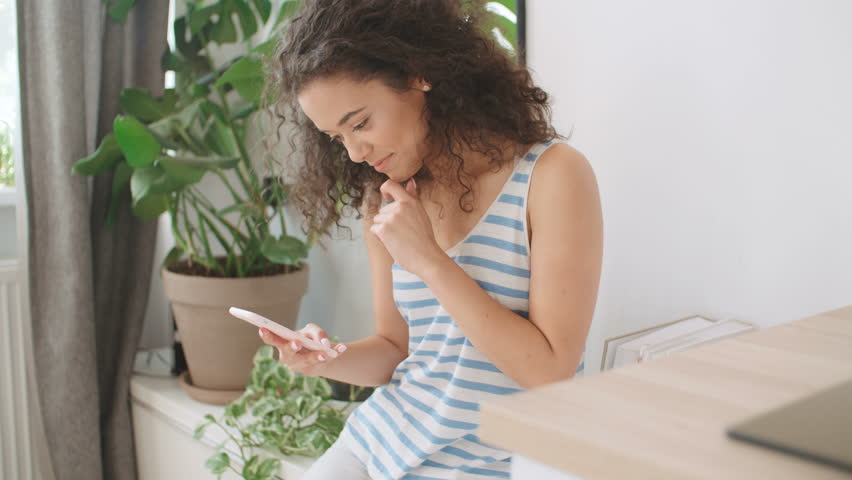 Young brunette woman using mobile phone at home.