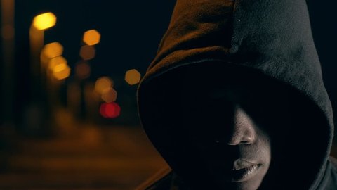Mysterious black man with hood in the city night looking at camera