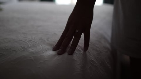 Shadowed hand rubbing across bed spread