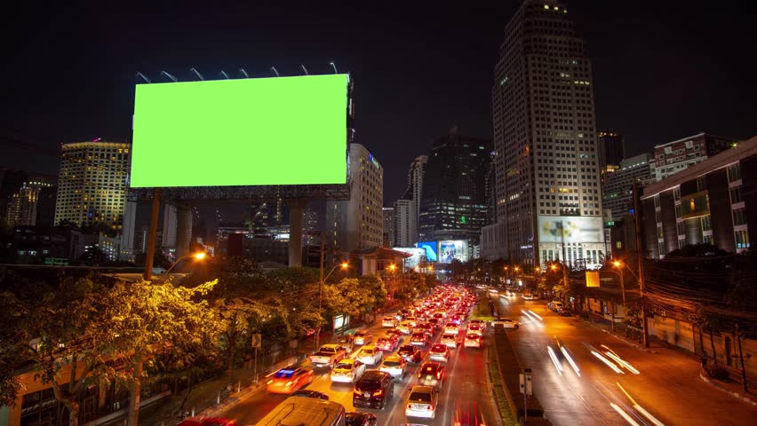 Time lapse: Billboard with green screen and city traffic light background at night. 4K Resolution. Royalty-Free Stock Footage #1019019433