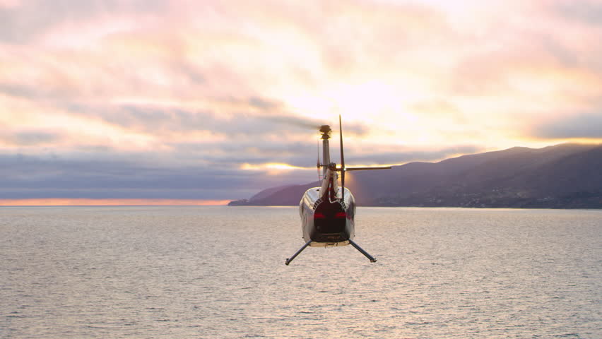Aerial view of helicopter flying over ocean shoreline city with mountains in the distance during purple sunset in Los Angeles, California. Wide long shot on 4K RED camera. Royalty-Free Stock Footage #1019021890