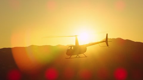 Aerial view of helicopter flying over mountains into the clouds during magical sunset in Los Angeles, California. Wide long shot on 4K RED camera.