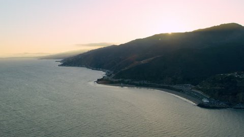 Aerial view of helicopter flying over mountain shoreline during beautiful sunset in Los Angeles, California. Wide long shot on 4K RED camera.