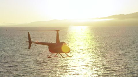 Aerial view of helicopter flying over ocean shoreline during beautiful sunset in Los Angeles, California. Wide long shot on 4K RED camera.