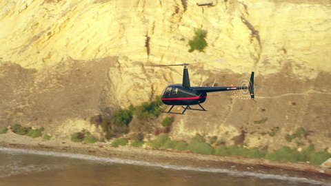 Aerial view of helicopter flying over ocean cliffs bluffs during golden hour in Los Angeles, California. Wide long shot on 4K RED camera.