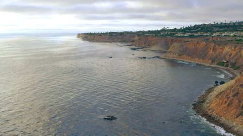 Aerial view of helicopter flying over ocean cliffs bluffs during a beautiful sunset in Los Angeles, California. Wide long shot on 4K RED camera.