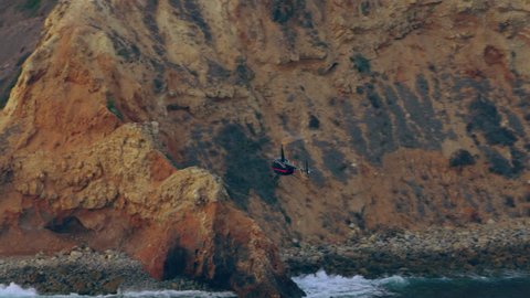 Aerial view of helicopter flying over ocean cliffs bluffs during a beautiful sunset in Los Angeles, California. Wide long shot on 4K RED camera.