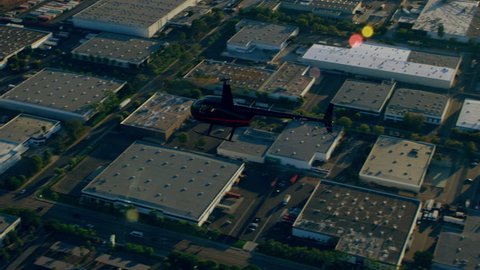 Aerial view of helicopter flying over city during a sunny blue sky day in Los Angeles, California. Wide long establishing shot with lens flare on 4K RED camera.