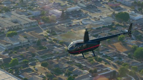 Aerial view of helicopter flying over city during a sunny blue sky day in Los Angeles, California. Wide long establishing shot on 4K RED camera.