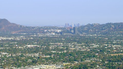 Aerial view of helicopter flying over city with downtown in background during the day in Los Angeles, California. Shot on 4K RED camera.