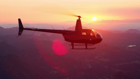 Aerial view of helicopter flying over mountain range during gorgeous pink sunset in Los Angeles, California. Wide long shot on 4K RED camera.