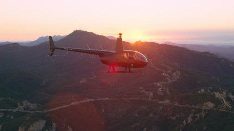 Aerial view of helicopter flying over mountain range during purple and pink sunset in Los Angeles, California. Wide long shot on 4K RED camera.