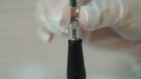 cosmetologist is holding a brush with a needle for permanent makeup of eye. Close-up. Modern methods of cosmetology. Blurred background