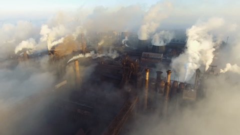 Aerial view. Pipes Throwing Smoke in the Sky. Large Plant on the Background of the City.