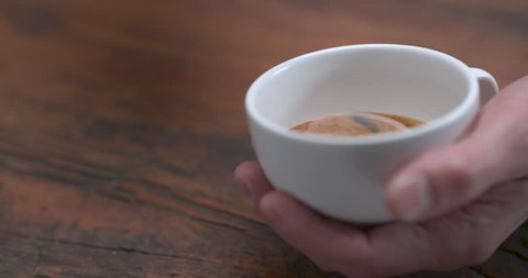 Barista making latte by pourring milk in white cup in ultra slow motion closeup