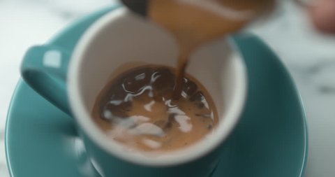Barista pourring espresso in blue small cup in ultra slow motion closeup with 4k Phantom Flex camera