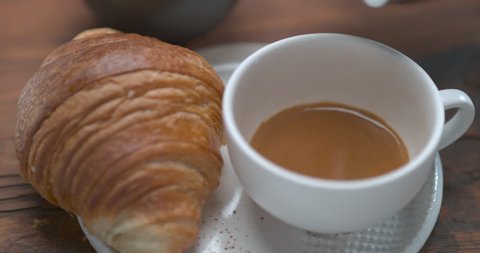 Mouth watering latte being poured in cup next to butter croissant ultra slow motion closeup with 4k Phantom Flex camera