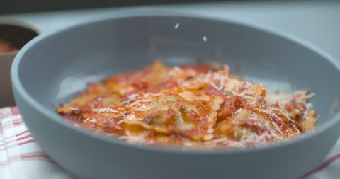 Parmesan cheese being grated onto tomato ravioli dish in bowl in ultra slow motion with 4k Phantom Flex camera